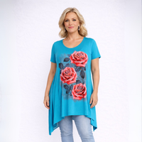 Woman wearing a turquoise tunic with floral designs on a white background