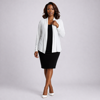 Woman wearing a white cardigan over a black dress on a gray background