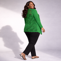 Woman wearing a green lace top and black pants on a white background