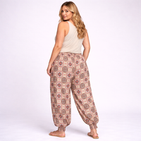 Woman wearing patterned pants and a beige top on a white background