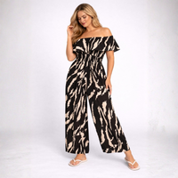 Woman wearing a black and beige patterned off-shoulder jumpsuit on a white background