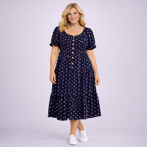 Woman wearing a navy dress with white polka dots on a light purple background