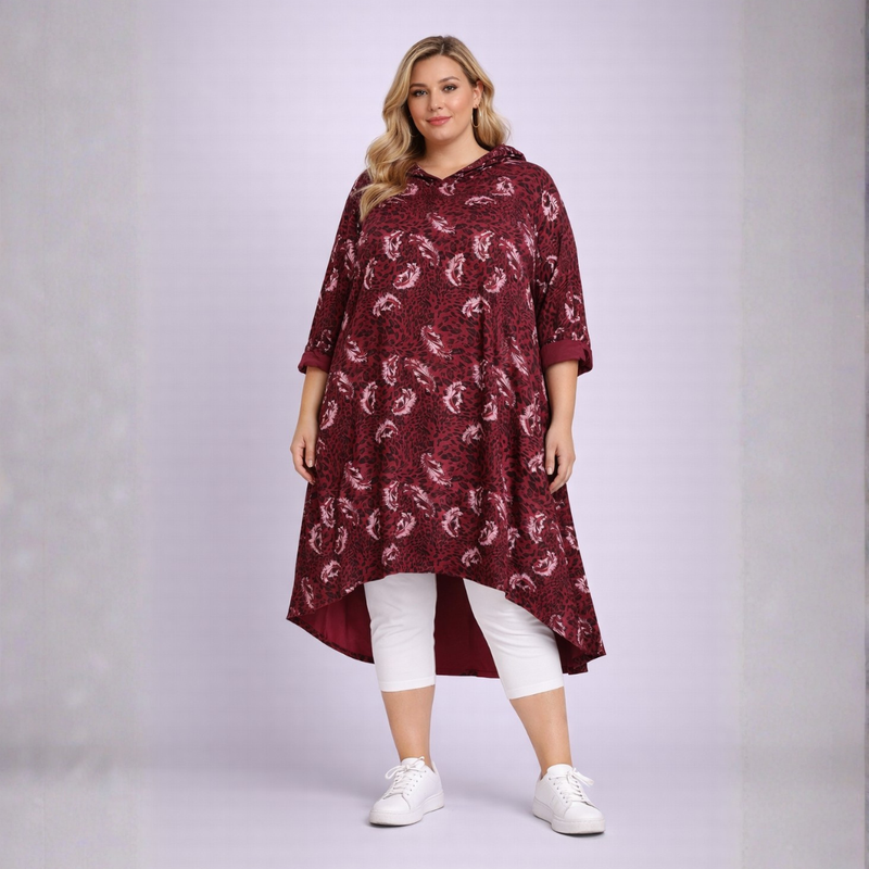 Woman wearing a burgundy patterned dress with white leggings and shoes on a light gray background