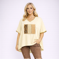 Woman wearing a beige top with leopard print and sequin details on a white background