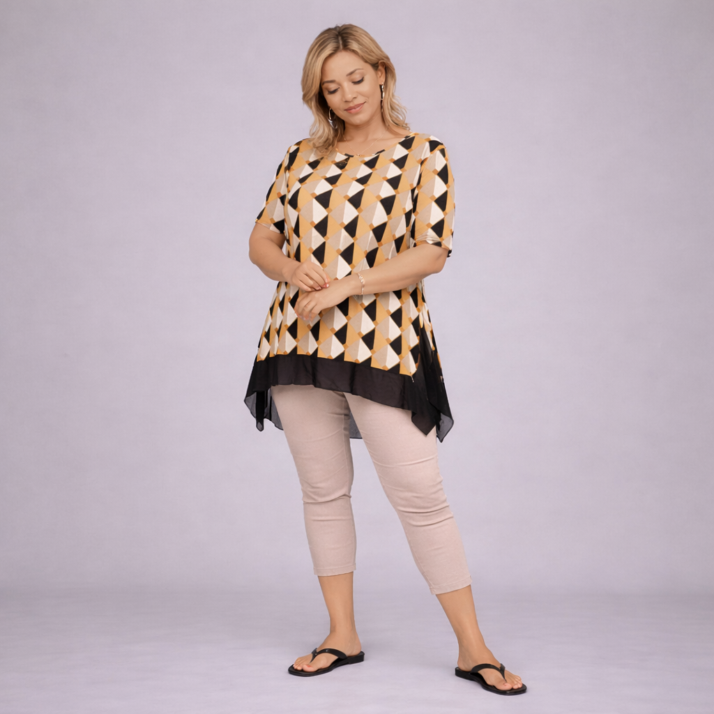 Woman wearing a patterned top and beige pants on a plain background