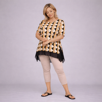 Woman wearing a patterned top and beige pants on a plain background