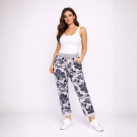 Woman wearing a white tank top and floral pants on a white background