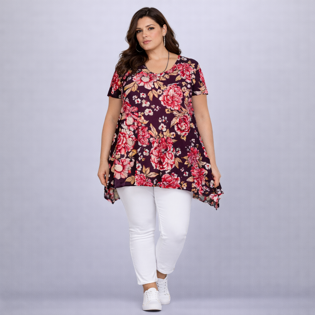 Woman wearing a floral tunic and white pants on a gray background