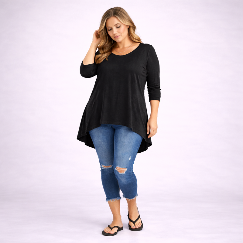 Woman wearing a black long-sleeve top and blue jeans on a white background