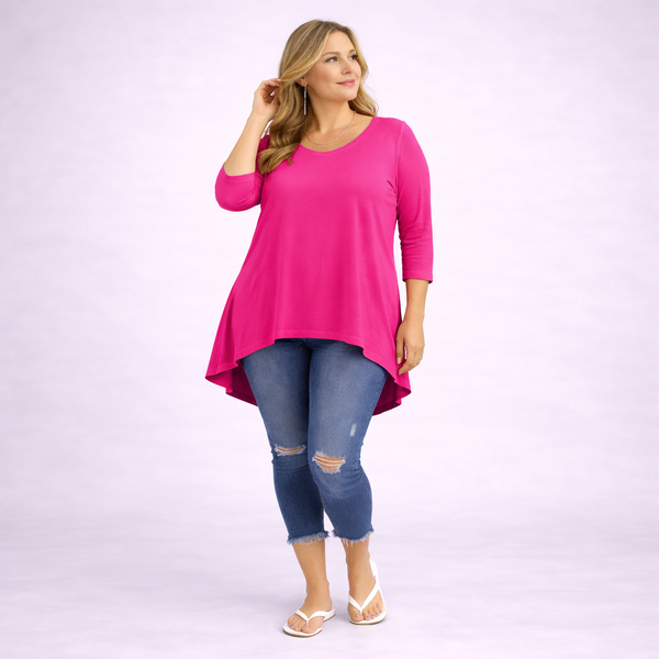 Woman wearing a bright pink top and blue jeans on a light purple background