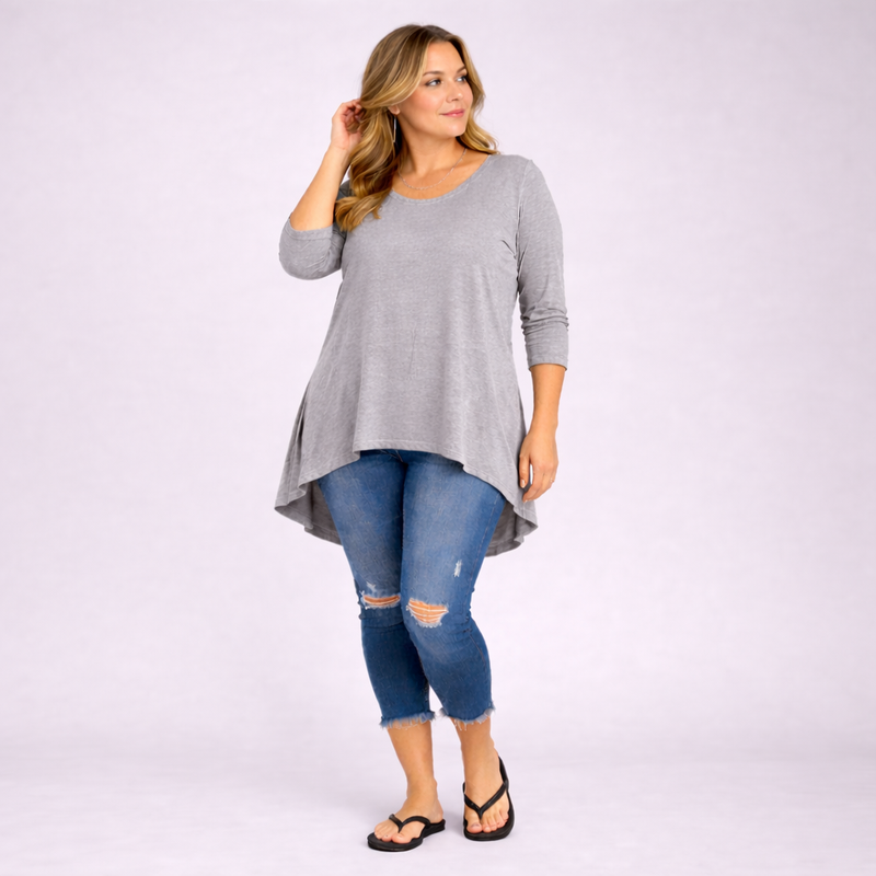 Woman wearing a gray long-sleeve top and blue jeans on a white background