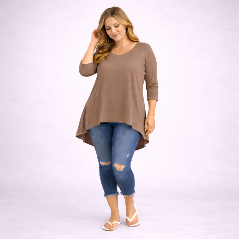 Woman wearing a brown long-sleeve top and blue jeans on a white background
