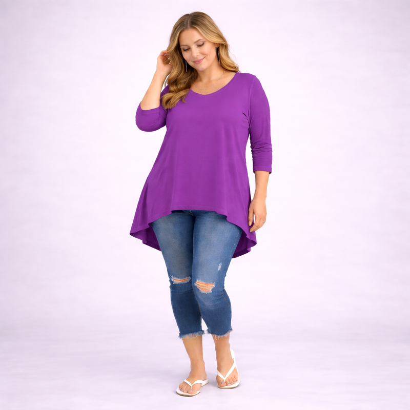 Woman wearing a purple long-sleeve top and blue jeans on a white background
