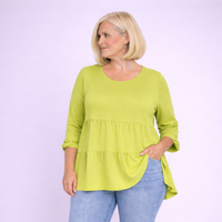 Woman wearing a green blouse and blue jeans against a light purple background